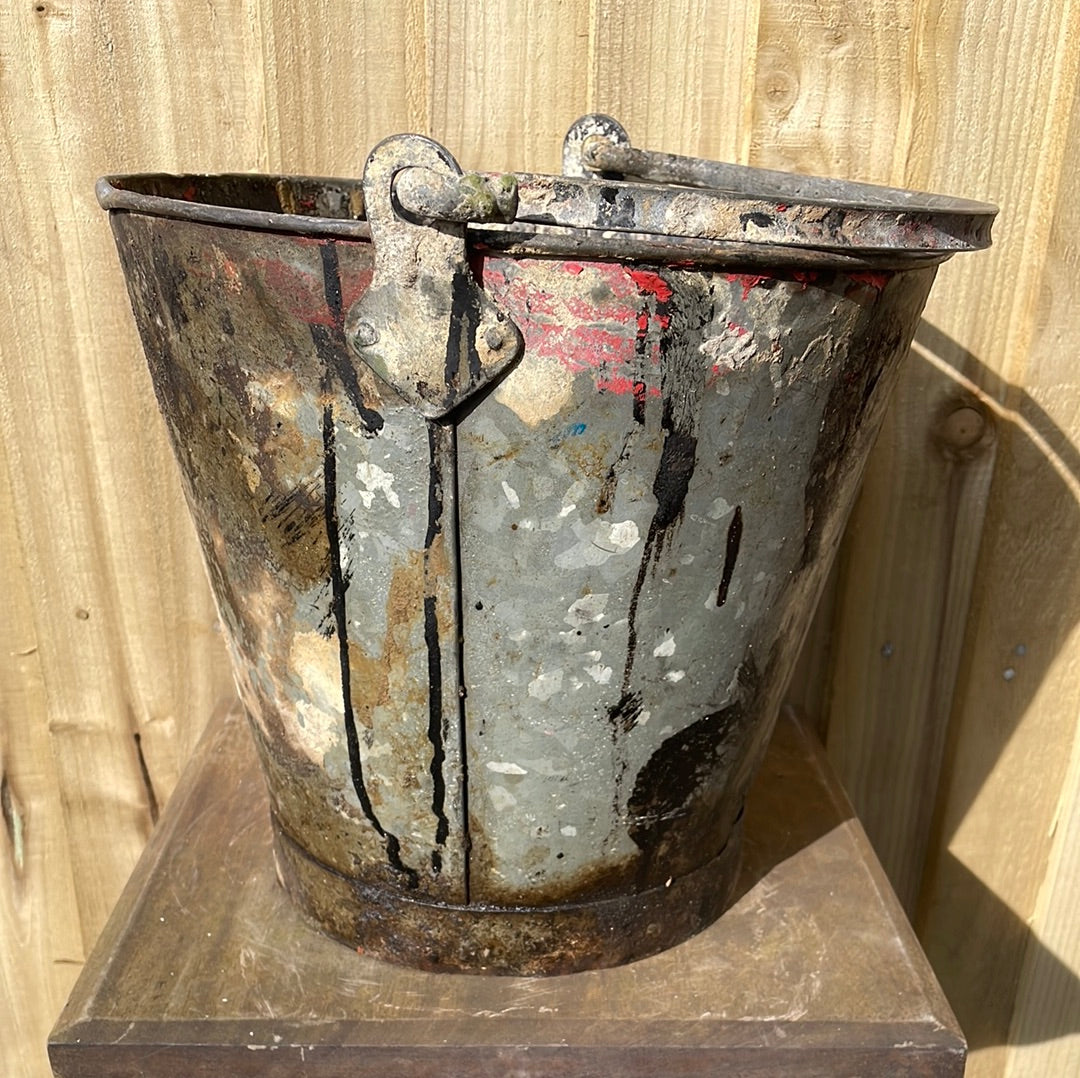 Rustic galvanised bucket planter with black paint splashes.