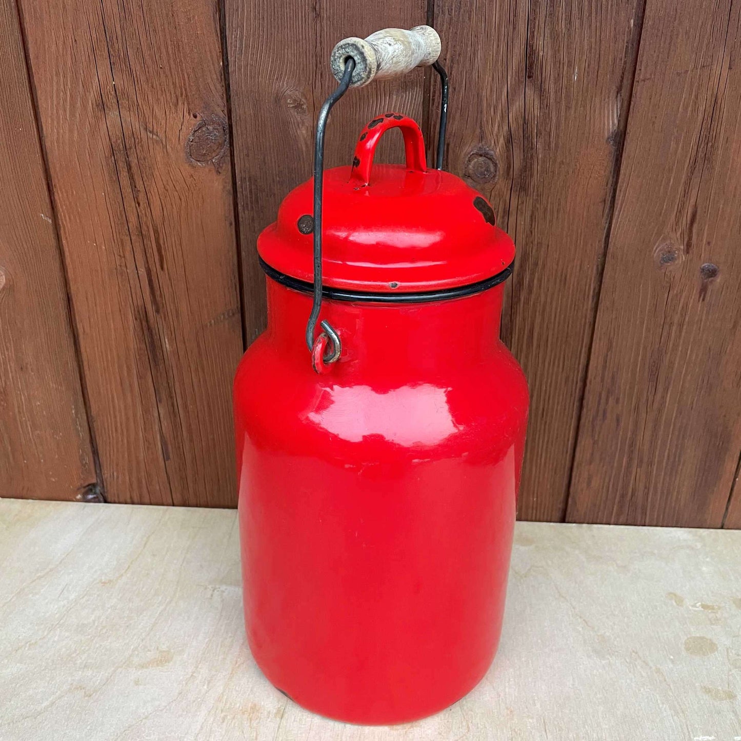 Red enamelled churn container with lid.