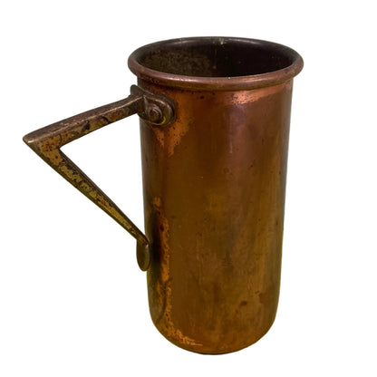 Vintage copper measuring cup against a white background.