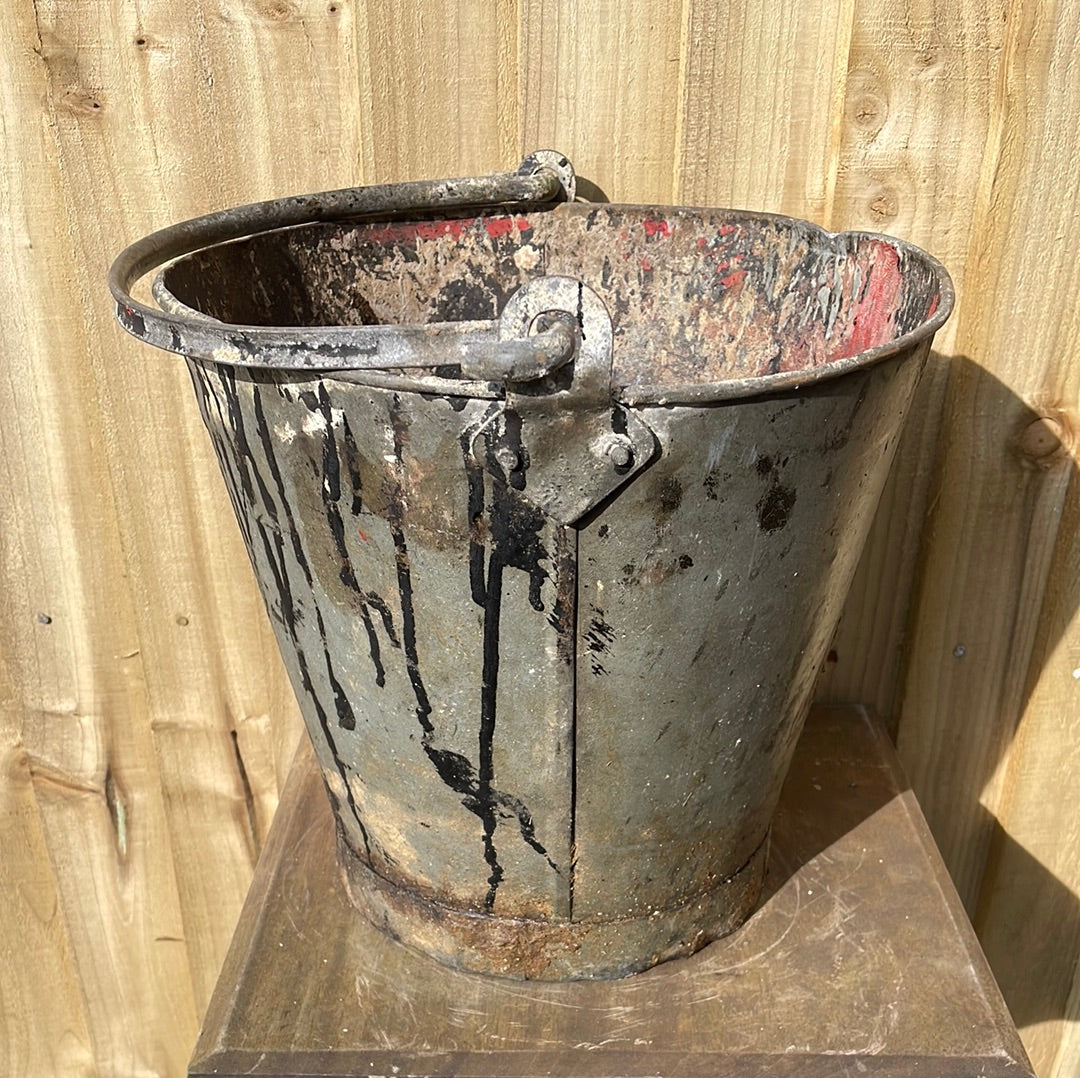 Rustic galvanised bucket planter with black paint splashes.