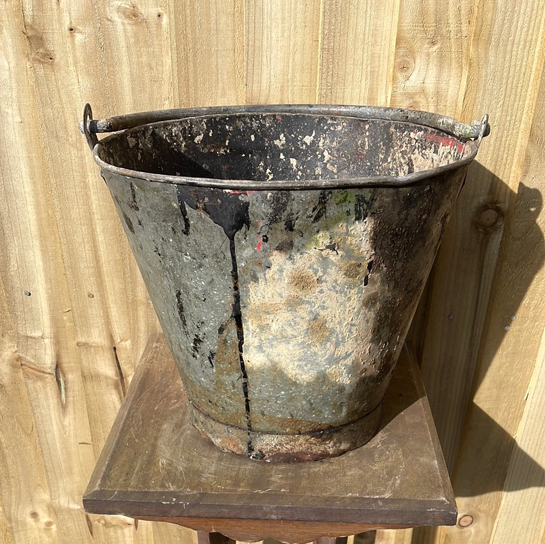 Rustic galvanised bucket planter with black paint splashes.