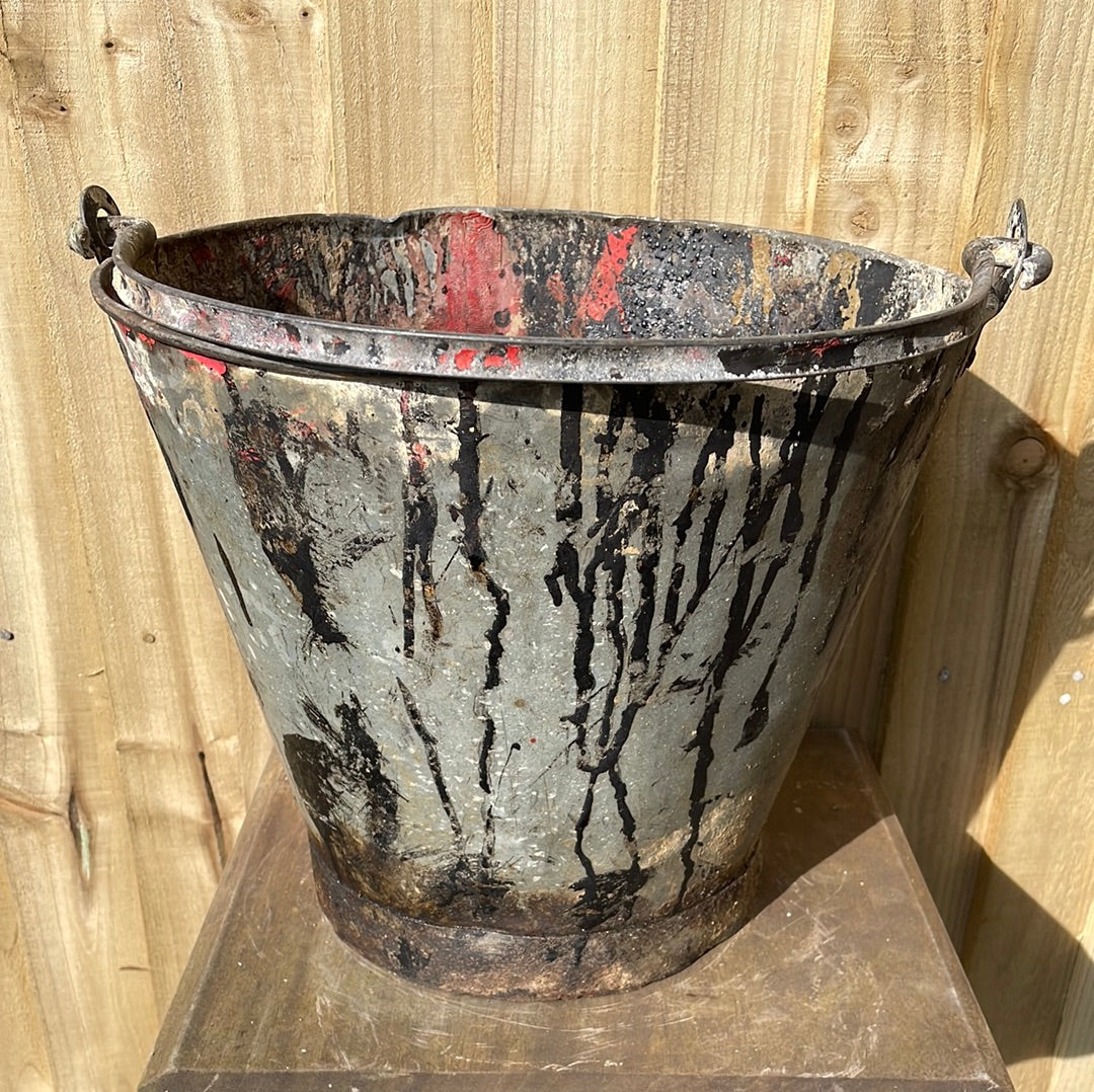 Rustic galvanised bucket planter with black paint splashes.