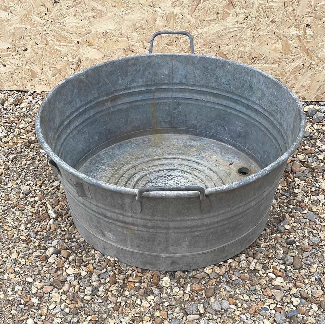 Round shallow galvanised straight sided tub planter with two handles.