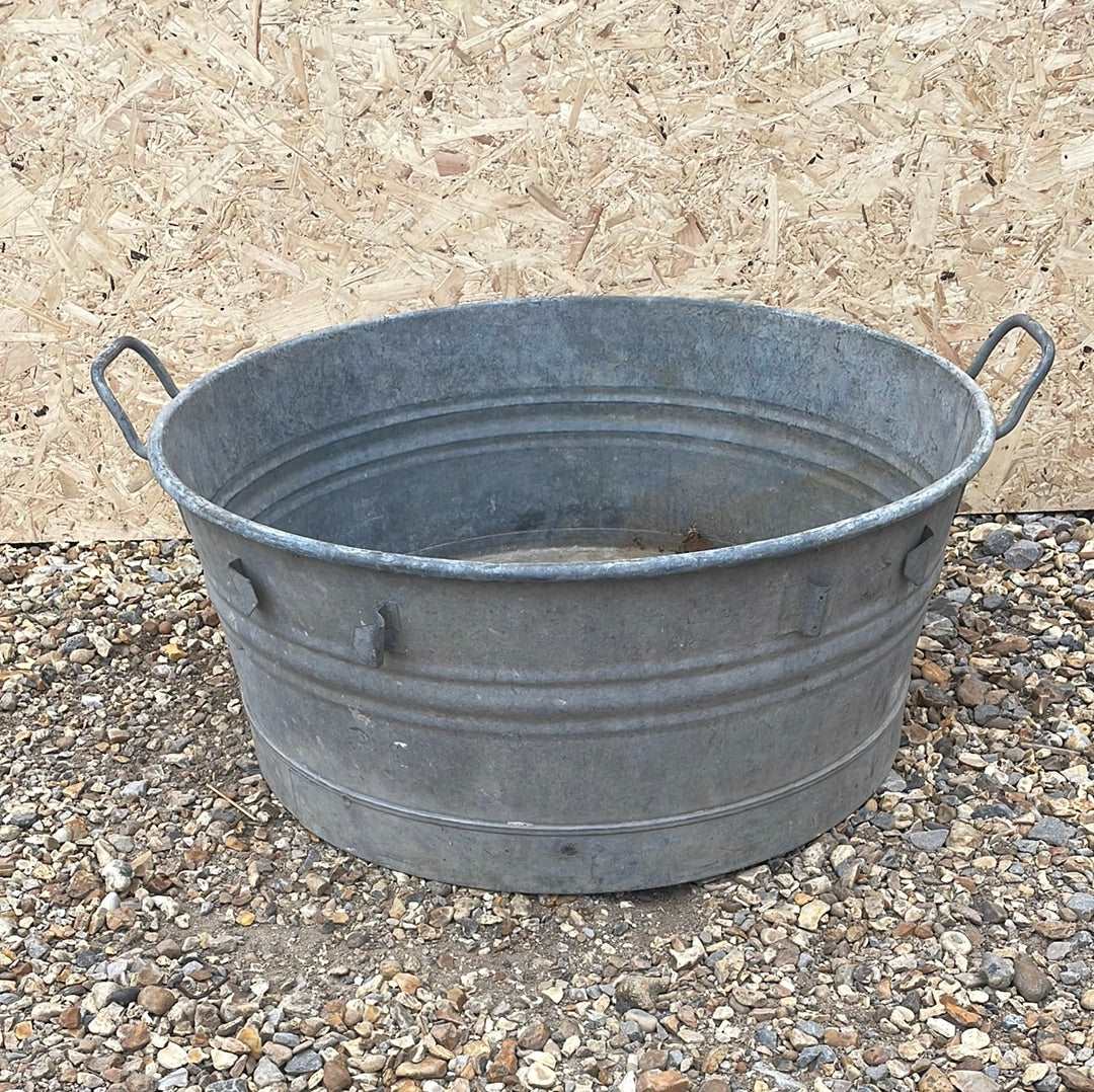 Round shallow galvanised straight sided tub planter with two handles.