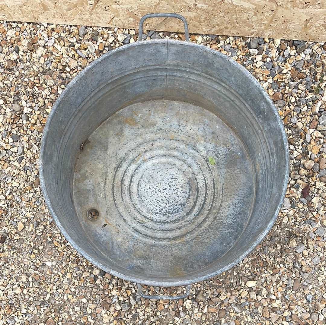 Round shallow galvanised straight sided tub planter with two handles.